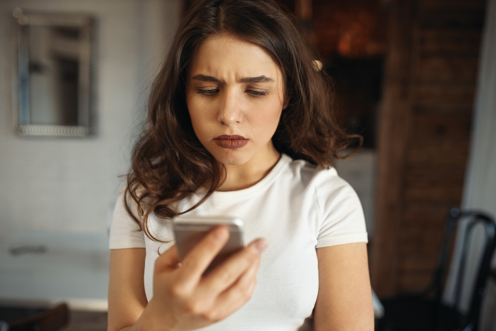 Kobieta patrząca ze zmartwieniem na telefon