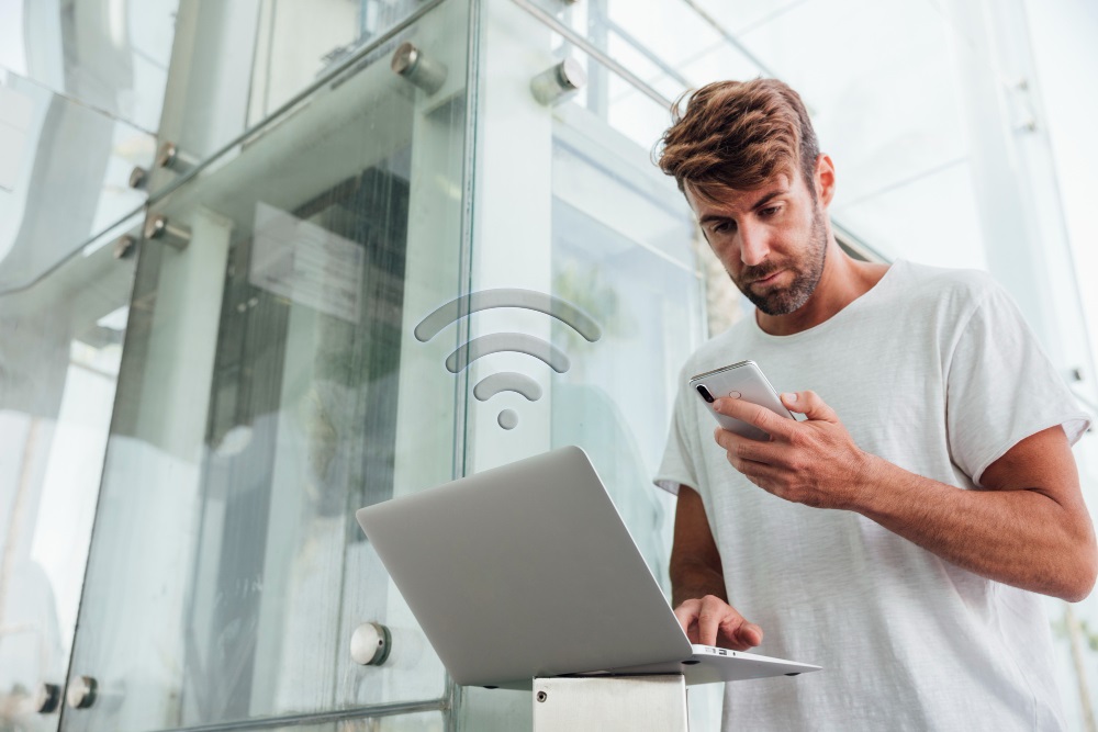 mężczyzna korzystający z telefonu i laptopa
