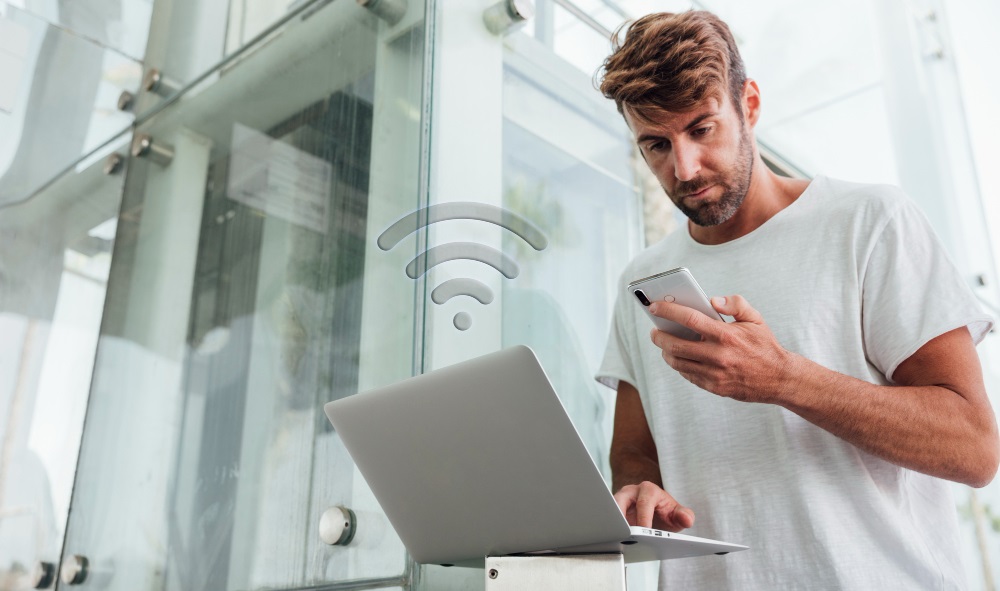 mężczyzna korzystający z telefonu i laptopa