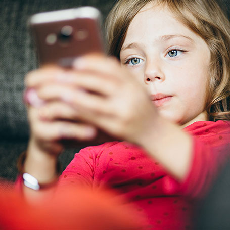 Dziewczynka patrzy w telefon – dziecko w sieci