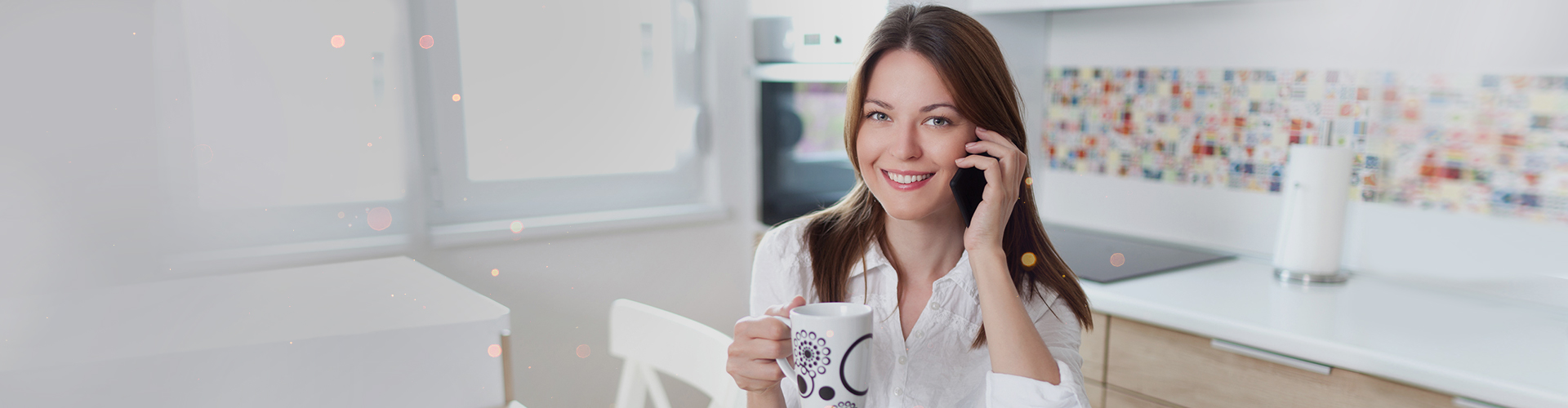 Uśmiechnięta kobieta rozmawia przez telefon komórkowy, trzymając kubek