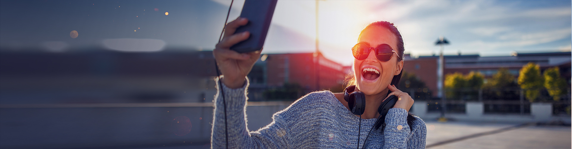 Uśmiechnięta kobieta w okularach patrząca na swój smartfon